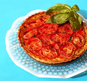 beautifully present frittata with roasted tomatoes and basil on top